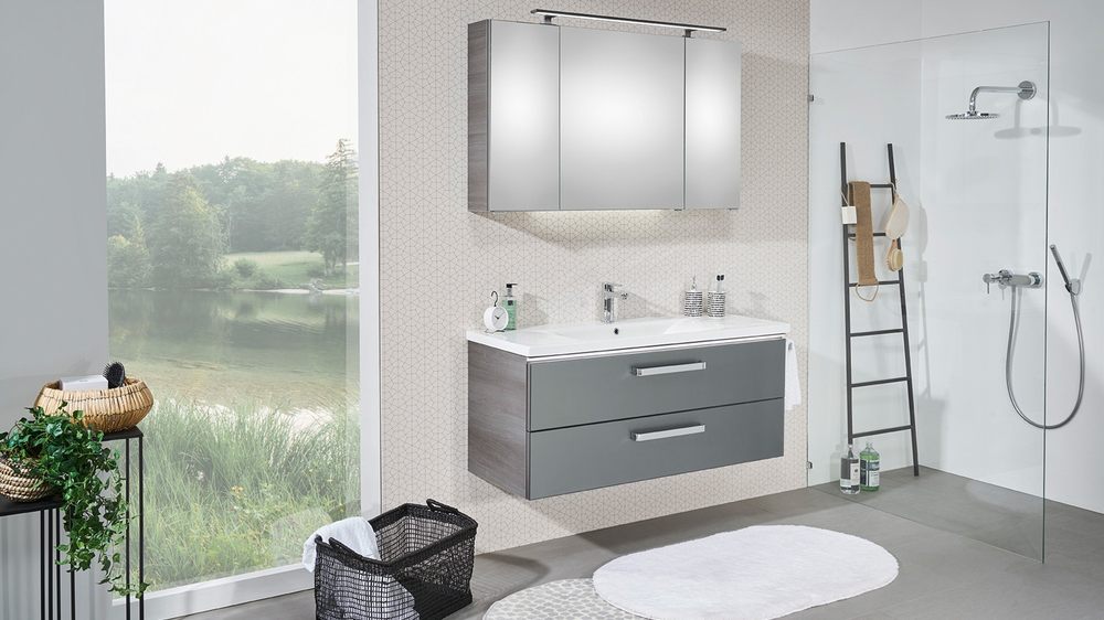 Grauer Badezimmerschrank und Spiegelschrank in einem lichtdurchfluteten Badezimmer 