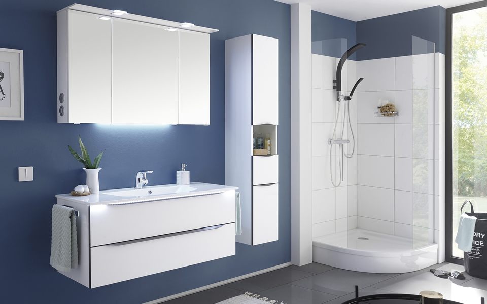 Weiße Badezimmermöbel mit einem beleuchteten Spiegelschrank 